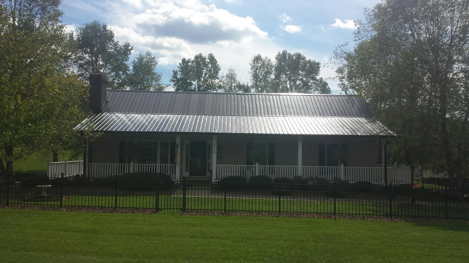 Gray metal roof on a brick ranch with a full width front porch — Gutter Guard Installation work by our crew in Columbia